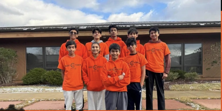 Rust in Piece FTC Team 19772 members wearing orange team shirts standing together at Princeton STEM Academy, showcasing our diverse and passionate robotics team